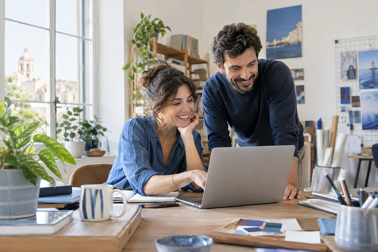 Due colleghi sorridenti collaborano a un progetto al computer.
